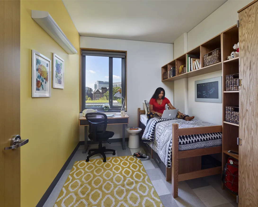 Student sitting on bed in Lauder College House bedroom