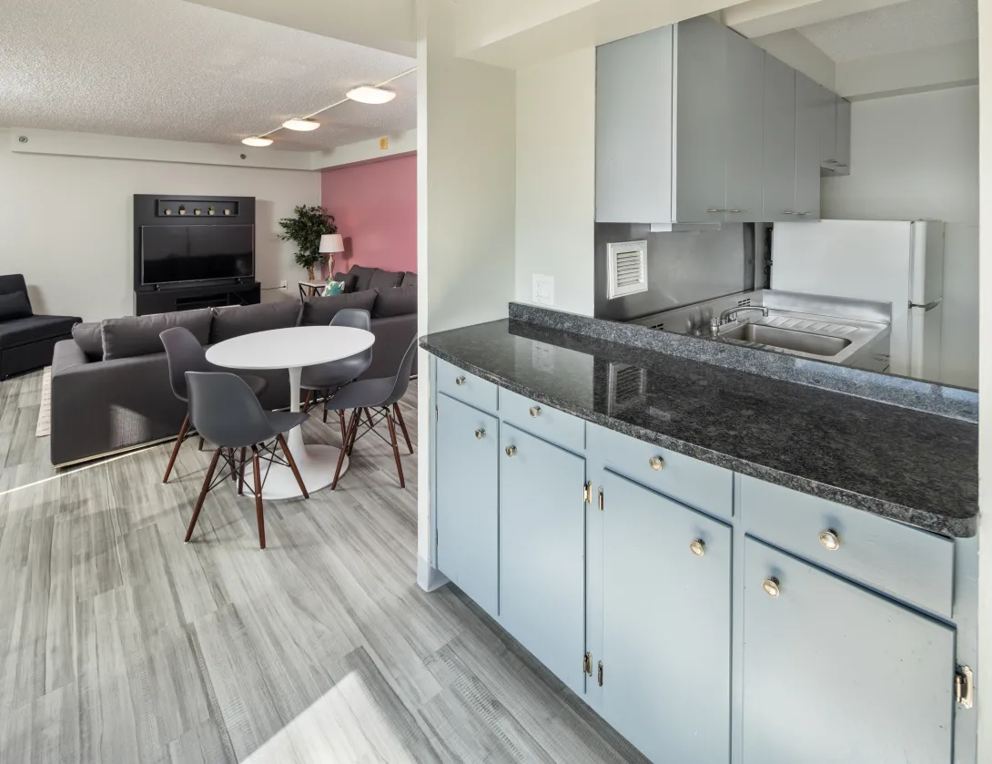 View of an apartment showing kitchen area with grey cabinets and a living room