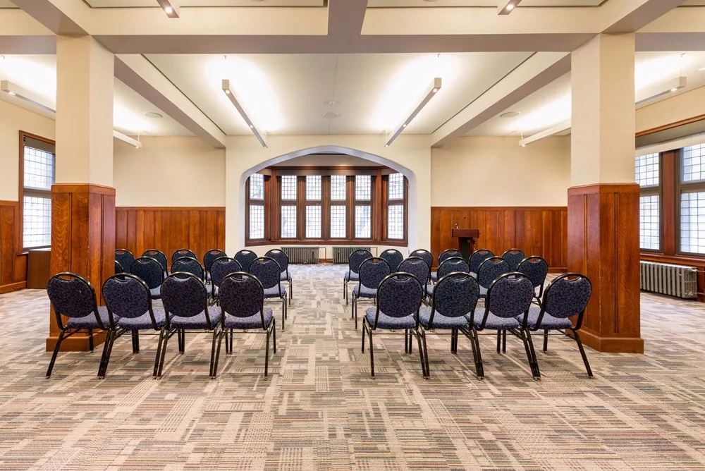 Room set in theater style seating facing a window framed by an archway