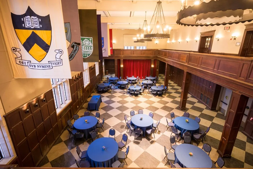 View of Hall of Flags from the balcony with 13 round tables around the floor surrounded by chairs.