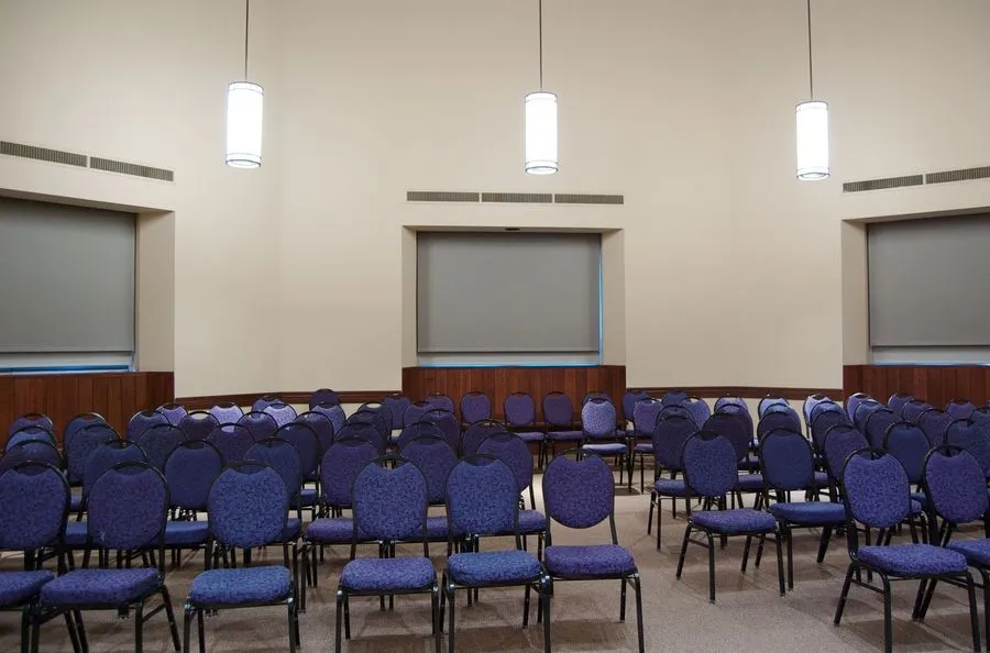 view of meeting room set up with blue chairs set theater style